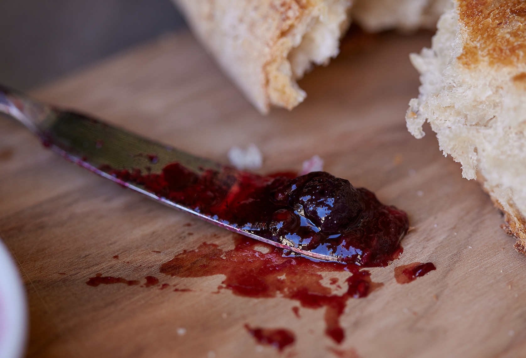 Jam on knife. Bread on cutting board